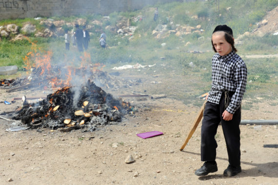 An Ultra-Orthodox Jewish boy walks by a fire burning leavened products before the start of the Jewish holiday Passover in Jerusalem